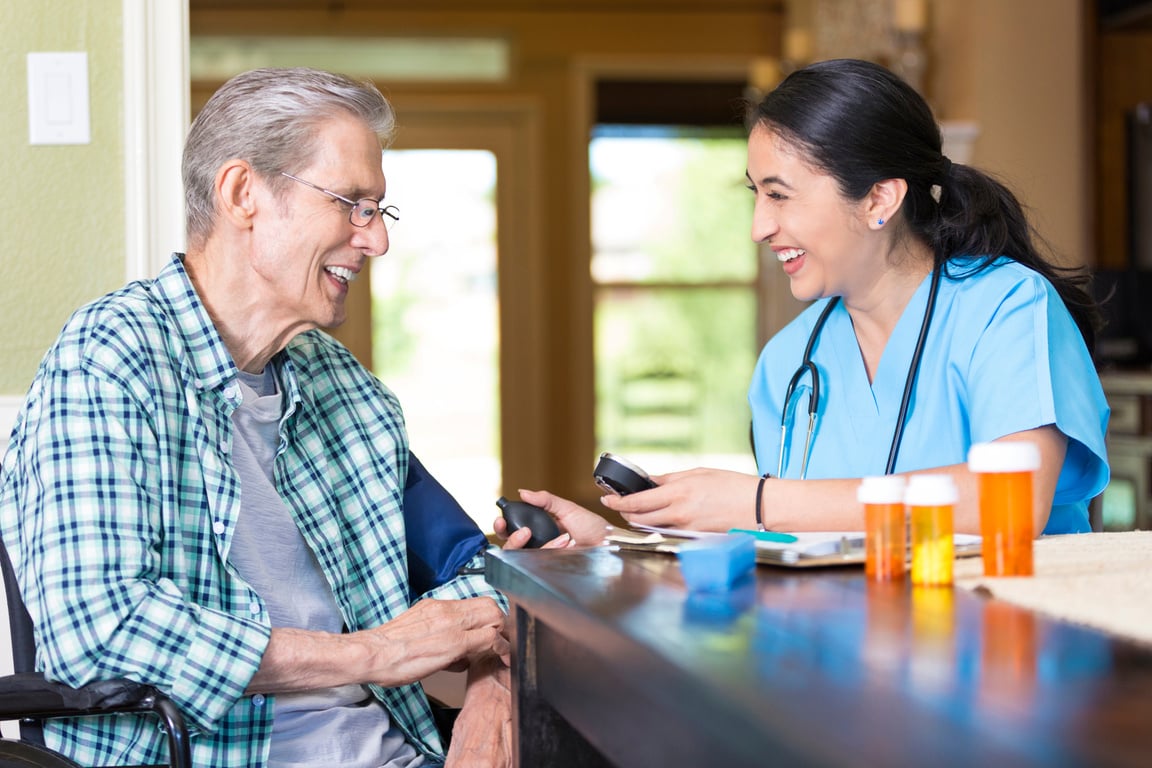 Home health care nurse visits with senior man